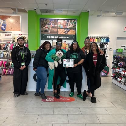 A local retail team gathers with a DJ's Day of Giving supporter plaque